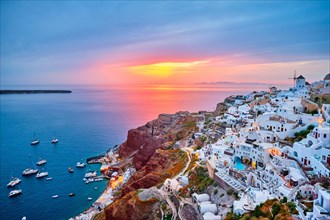 Famous greek iconic selfie spot tourist destination Oia village with traditional white houses and windmills in Santorini island on sunset in twilight