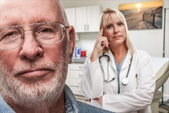 Empathetic doctor standing behind troubled senior adult man in office