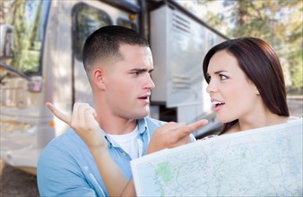 Young lost and confused military couple looking at map in front of RV