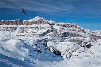 View of a ski resort piste with people skiing in Dolomites in Italy with cable car ski lift Ski area Arabba Arabba