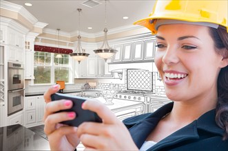 Female contractor using smart phone over kitchen drawing gradating to photo