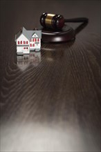 Gavel and small model house on wooden table
