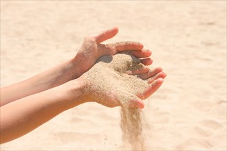 Sand running through hands on beach