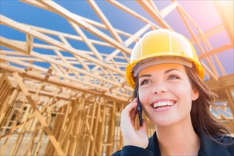 Female contractor in hard hat using cell phone at construction site