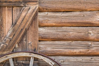 Abstract of vintage antique log cabin wall and wagon wheel