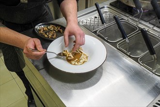 Chef plating pan cooked flambe atlantic squid with potato rich sauce cream reduction