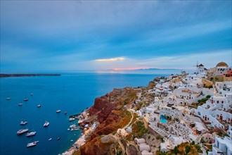 Famous greek iconic selfie spot tourist destination Oia village with traditional white houses and windmills in Santorini island on sunset in twilight