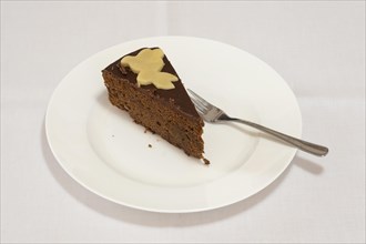 A piece of chocolate cake with a cake fork on a cake plate