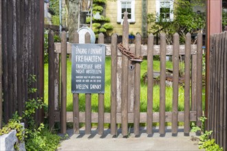Locked garden gate of a restaurant with notice