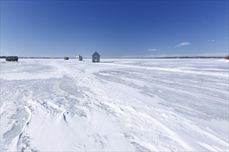Fishing huts on a wide and frozen riverscape