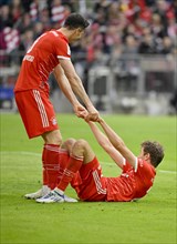 Robert Lewandowski FC Bayern Munich FCB helps Thomas Mueller FC Bayern Munich FCB to his feet