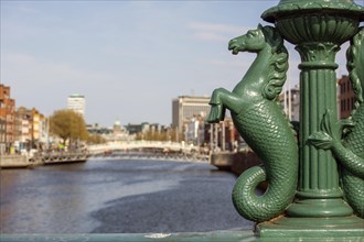 A green Irish seahorse on a bridge above the River liffey in Dublin with the famous Hapenny bridge in the background. Dublin