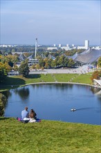 Two people sitting in the park with Olympic lake