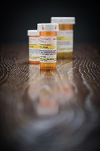 Variety of non-proprietary prescription medicine bottles on reflective wooden surface