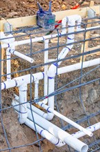 Newly installed PVC plumbing pipes and steel rebar configuration at construction site