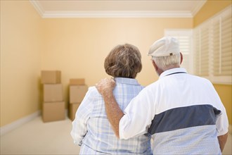 Hugging senior couple in room looking at moving boxes on the floor