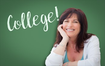College written on green chalkboard behind smiling middle aged woman