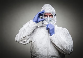 Man with intense expression wearing HAZMAT protective clothing against A gray background