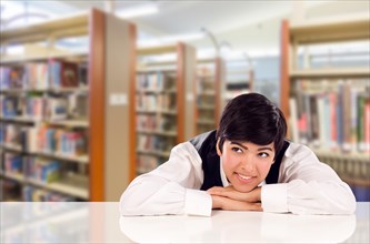 Young female mixed-race student daydreaming in library looking to the left
