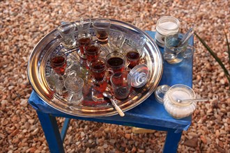 Silver tray with tea glasses stands on a blue table