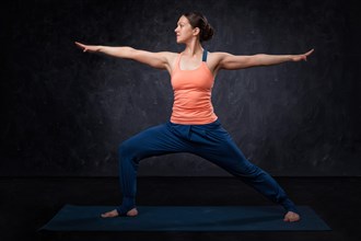 Beautiful sporty fit yogini woman practices yoga asana Virabhadrasana 2