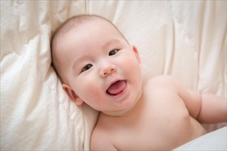 Young mixed-race chinese and caucasian baby boy having fun on his blanket