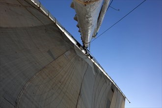 White sail of a sailboat against blue sky