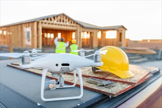 Drone quadcopter next to hard hat helmet at construction site with workers behind