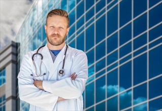 Handsome young adult male doctor with beard in front of hospital building