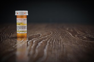 Non-Proprietary prescription medicine bottle on reflective wooden surface