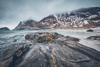 Rocky coast of fjord of Norwegian sea in winter with snow. Haukland beach