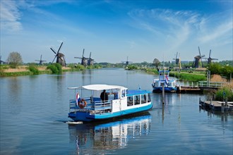 Netherlands rural landscape with tourist boat and windmills at famous tourist site Kinderdijk in Holland