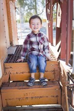 Cute young mixed-race boy having fun outside sitting on railroad car steps
