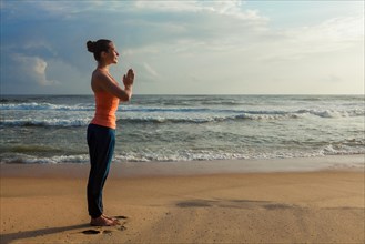 Woman doing Ashtanga Vinyasa Yoga asana Tadasana Samasthiti yoga posture on beach