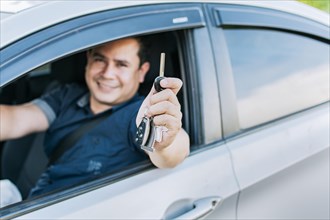 A man in his vehicle showing his new car keys