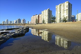 High-rise buildings with flats reflected in the water on the beach