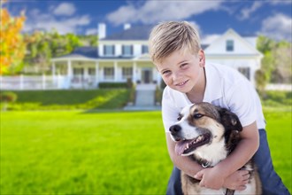 Happy young boy and his dog in front yard of their house