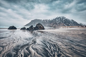 Rocks on beach of fjord of Norwegian sea in winter with snow. Skagsanden beach