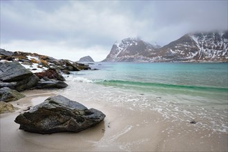 Rocky coast of fjord of Norwegian sea in winter with snow. Haukland beach