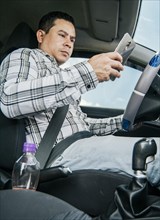 Man sitting in his car texting with his cell phone