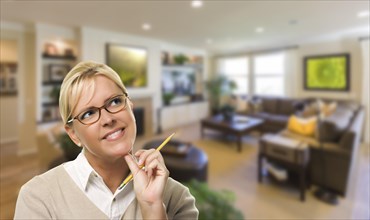 Attractive daydreaming woman with pencil inside beautiful living room