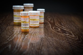 Variety of non-proprietary prescription medicine bottles on reflective wooden surface