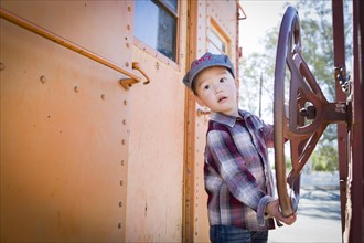Cute young mixed-race boy having fun outside on railroad car