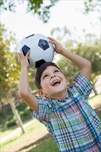 Cute young boy playing with soccer ball outdoors in the park