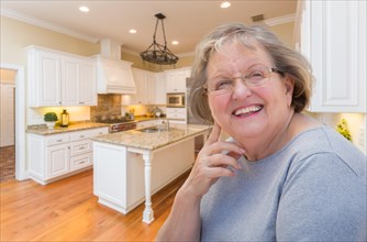 Happy senior woman sitting in custom kitchen interior