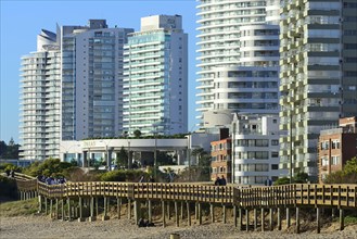 Wooden jetty on the beach in front of high-rise buildings with flats