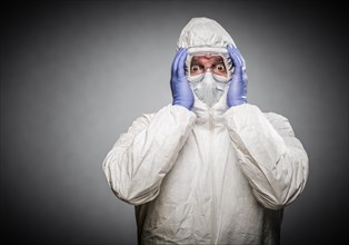 Man holding head with hands wearing HAZMAT protective clothing against A gray background