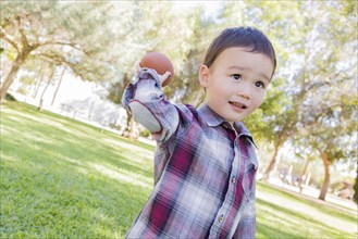 Adorable mixed-race boy playing football outside at the park
