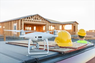 Drone quadcopter next to hard hat helmet at construction site with worker behind