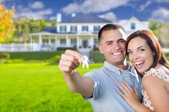 mixed-race excited military couple in front of new home showing off their house keys